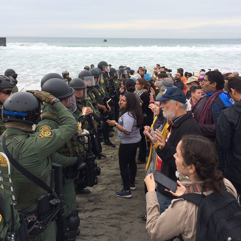 Protesters face are met by a line of heavily armed border agents at the US-Mexico border in Tijuana