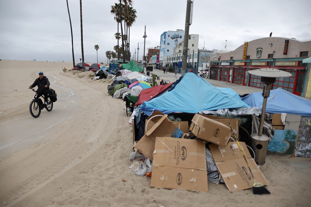 Tents of people experiencing homelessness line the bike path on Venice Beach in Los Angeles, California, April 13, 2021. Photo by Lucy Nicholson/Reuters