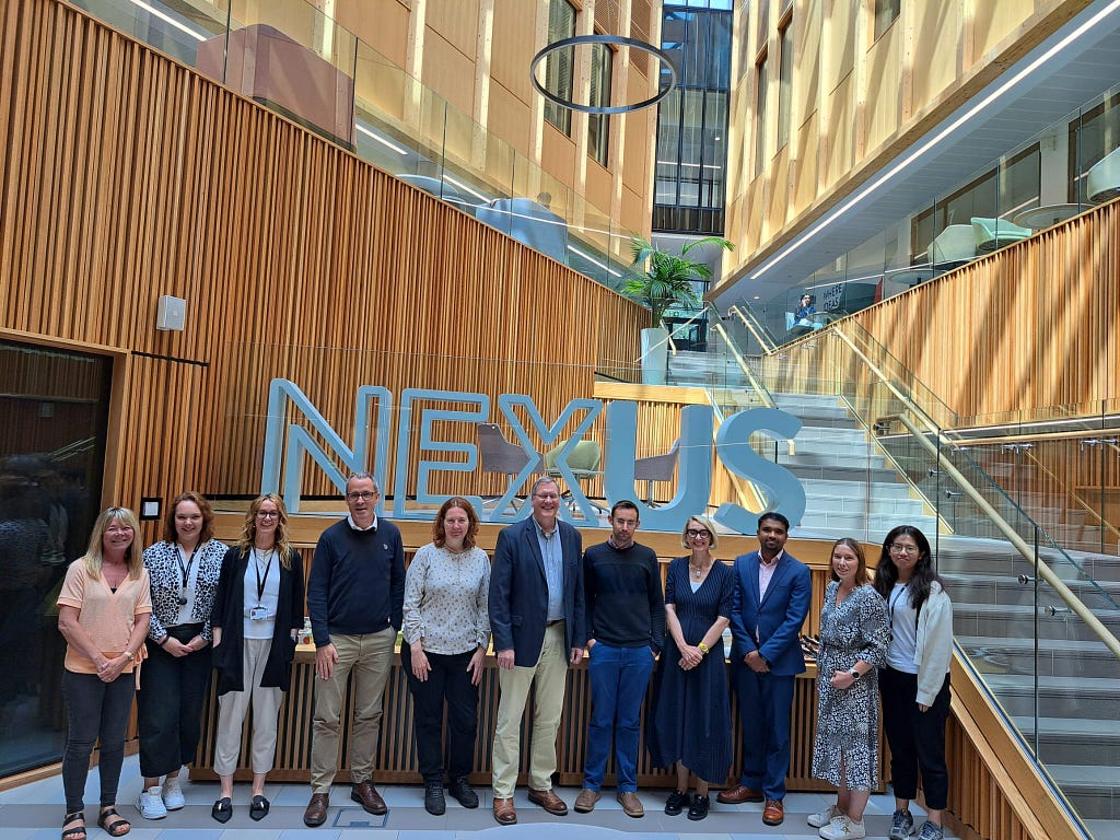 Members of the Global Food and Environment Institute’s Executive Group and External Advisory Board stand together for a photo. The sign for Nexus (based at the University of Leeds) is visible behind them.