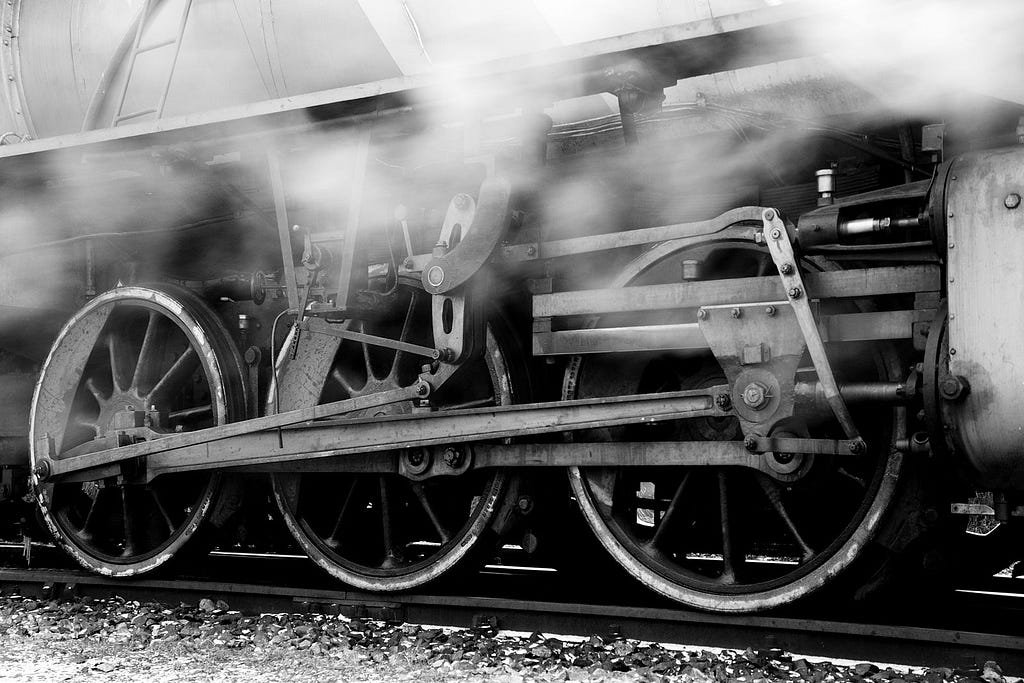 A black and white picture of a train with smoking wheels