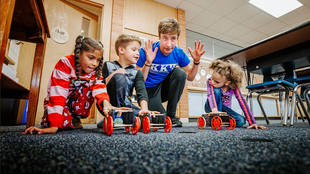 Spencer Knight gets three students and their rubber-band powered cars lined up for a race.