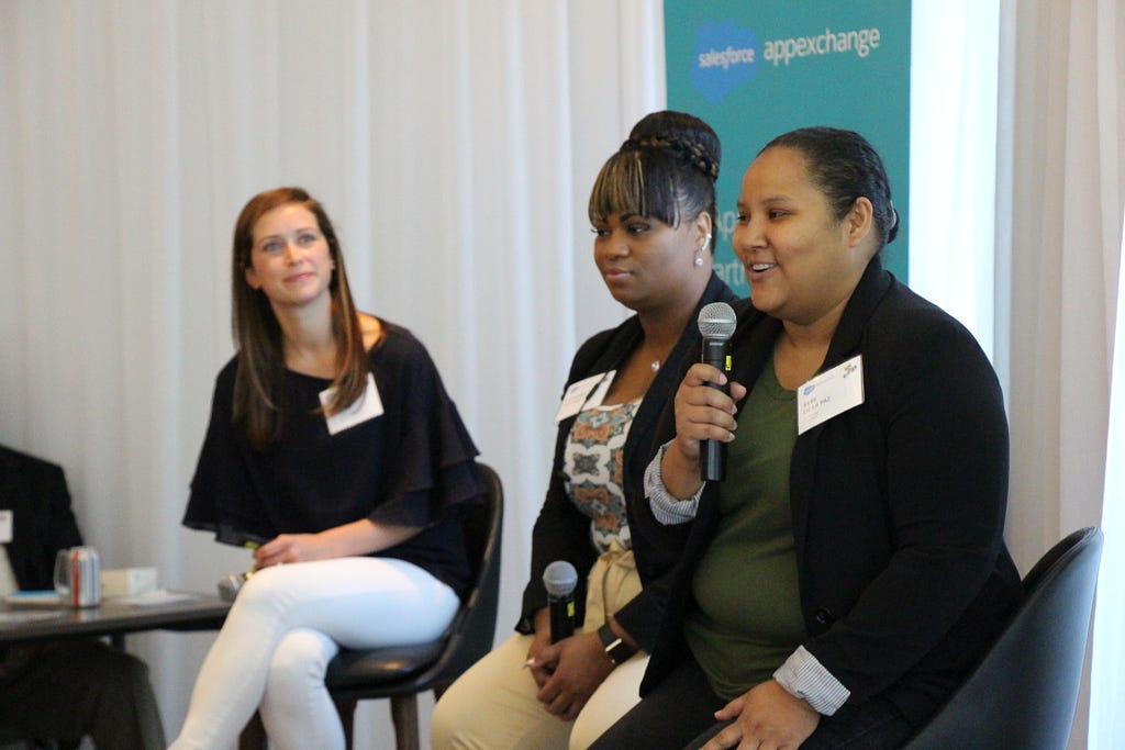 Three women speaking in a room in front of a Salesforce AppExchange logo