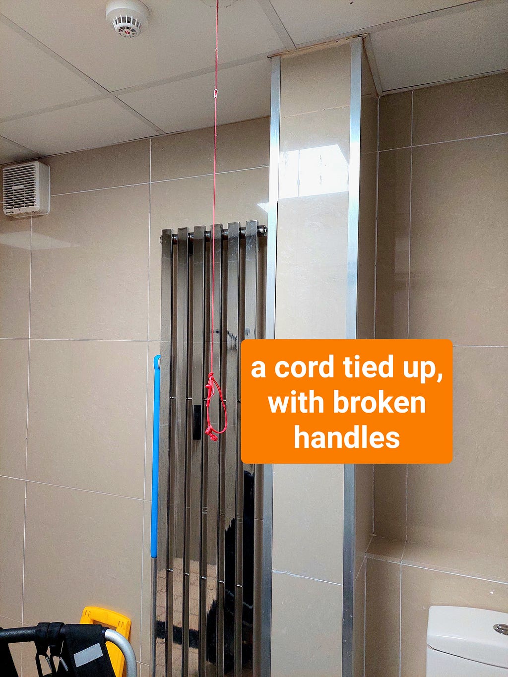 two images of the emergency pull cord in the accessible changing room in the spa. The cord is hanging from the ceiling but stops around a metre off the ground. There are the broken remains of one handle, tangled in the cord.