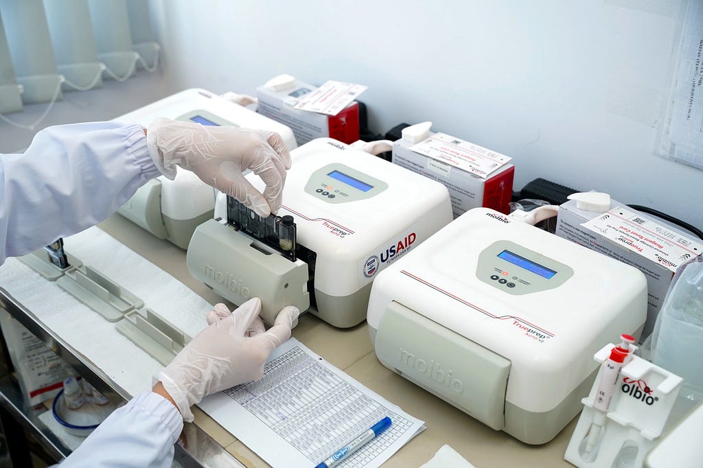 A health care worker’s gloved hands are seen using diagnostic testing equipment that can rapidly diagnose TB.