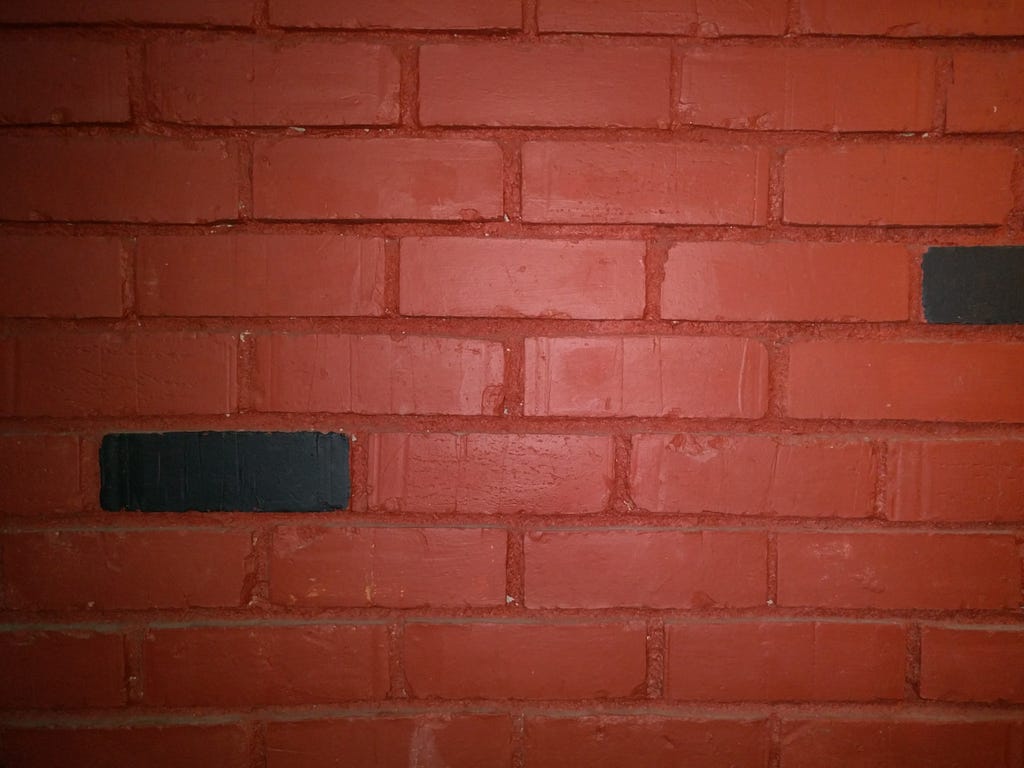 Two bricks painted black stand out in a wall of red bricks