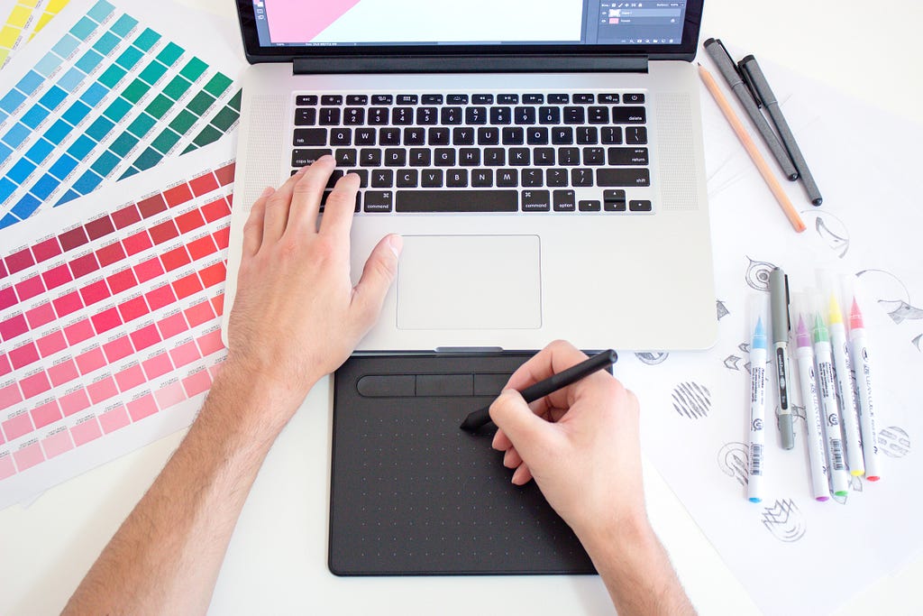 a graphic artist at work on a table with color palette samples