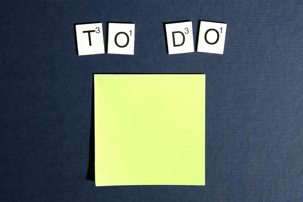 Letter tiles arranged to spell “to do” on top of a blank post-it note