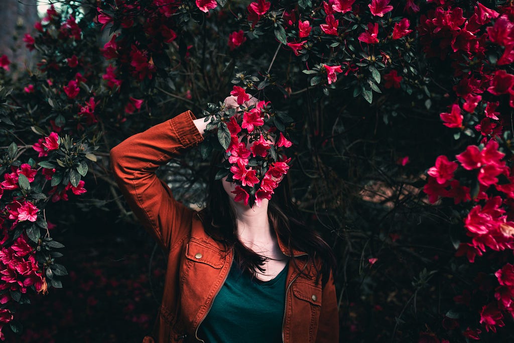 Woman holding a bunch of flowers obscuring her face