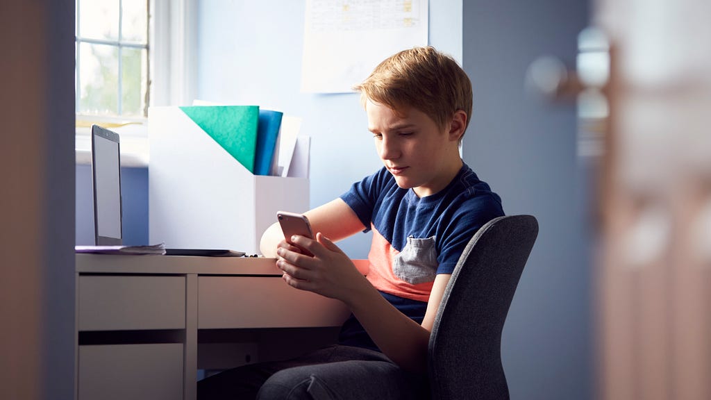 Niño mirando un móvil en su escritorio