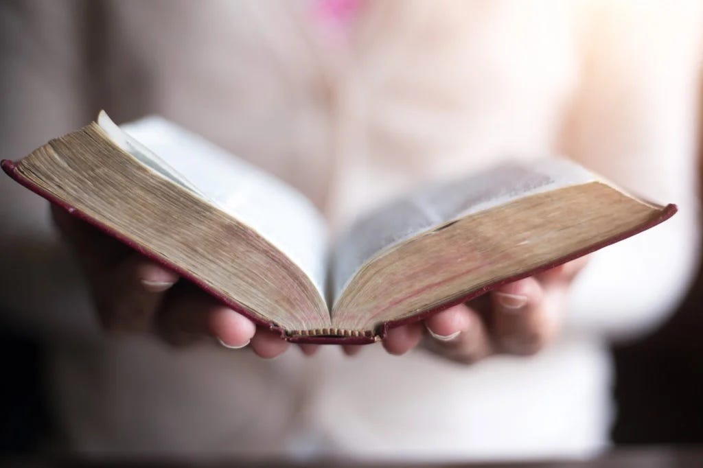 Bible held open in person’s hands.