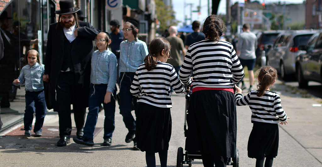 Two Hasidic families walk in opposite directions on a NYC street