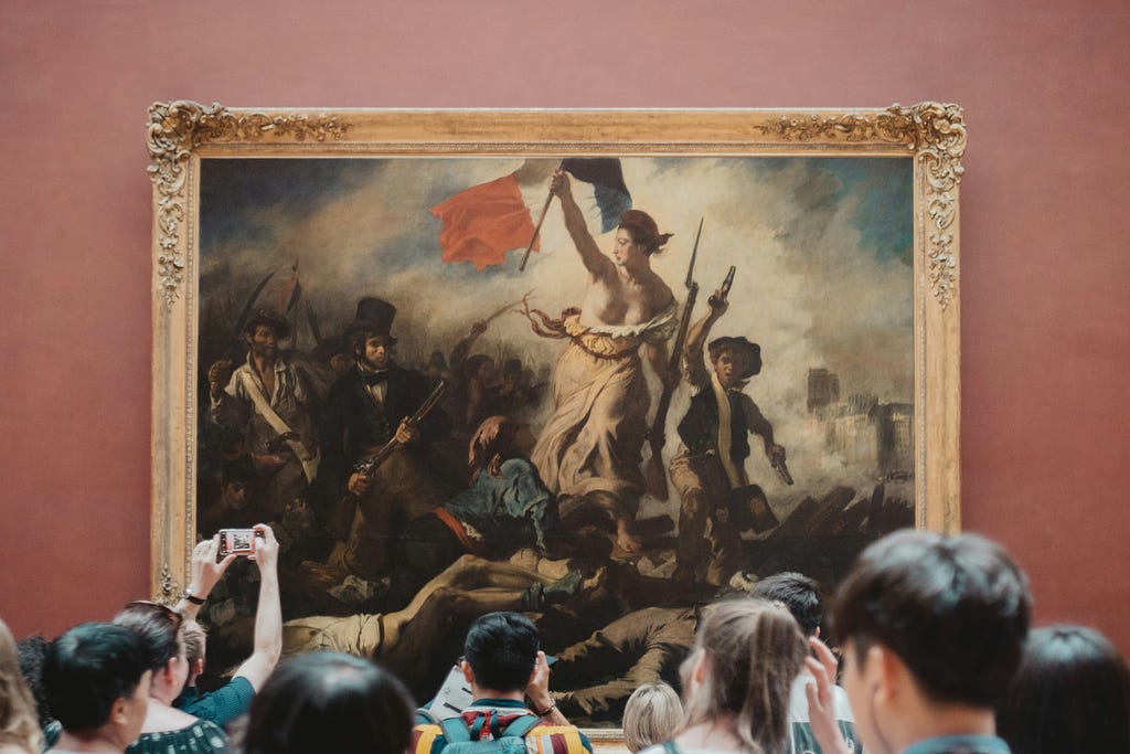 Tourists staring at a painting of “Liberty leading the people” in a museum with pink walls.