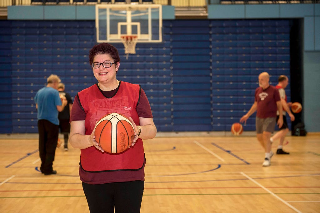 A woman smiles at the camera holding a basketball