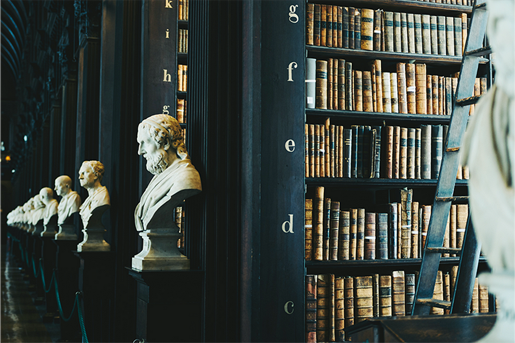 Biblioteca antiga na Irlanda, com bustos de filósofos na frente de cada corredor de livros.