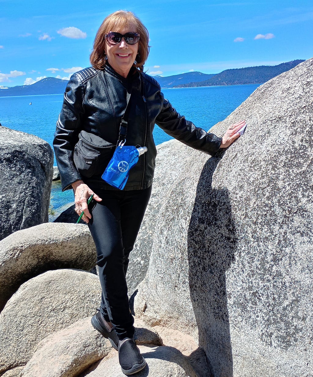 Author Judith Valente stands on top of and surrounded by hugh boulders left by an ancient glacier on the shore of Lake Tahoe near Reno, NV.