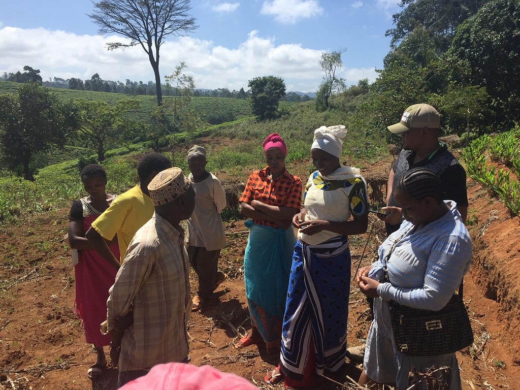 Farmers standing outside in a group discussing terracing, crop residue management and soil health.