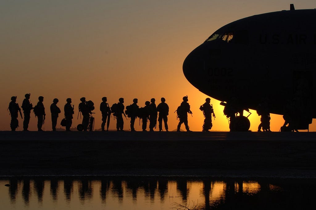 Soldiers waiting in line to board a plane at sunset