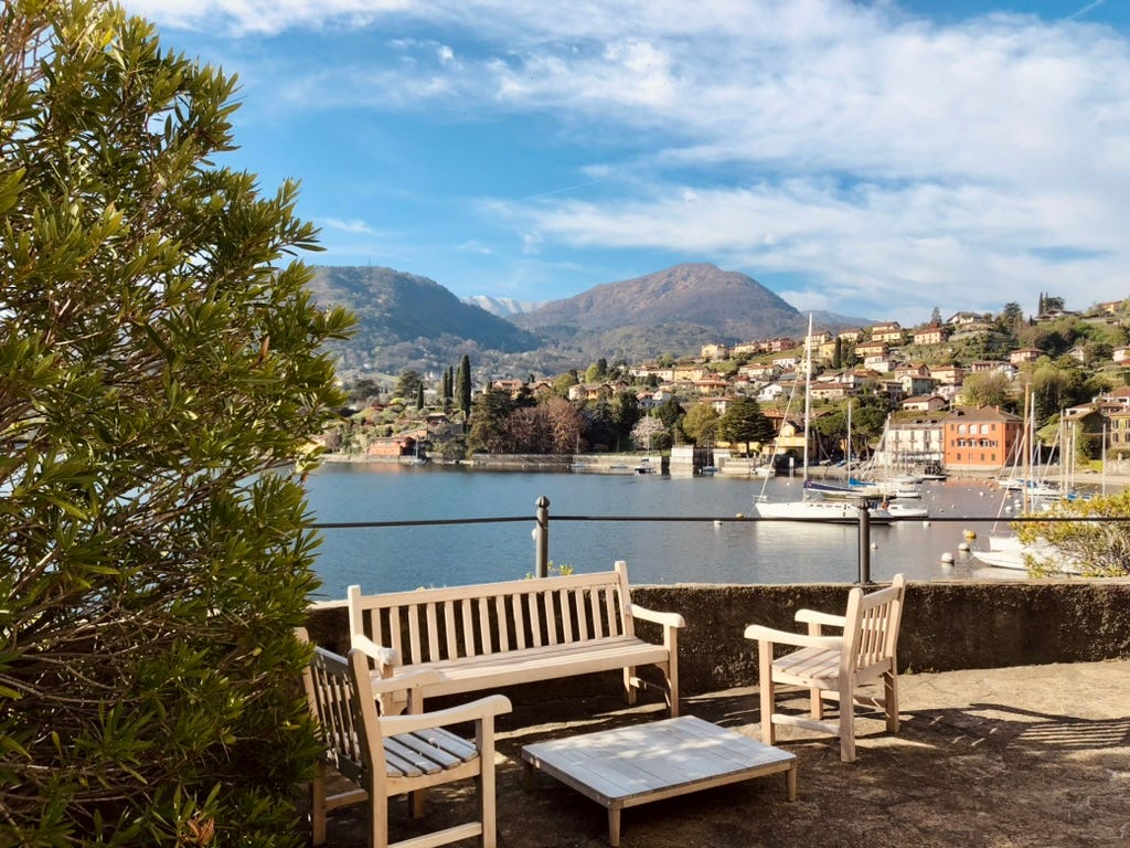 Benches and a small table at the side of the lake with mountains the in the background.