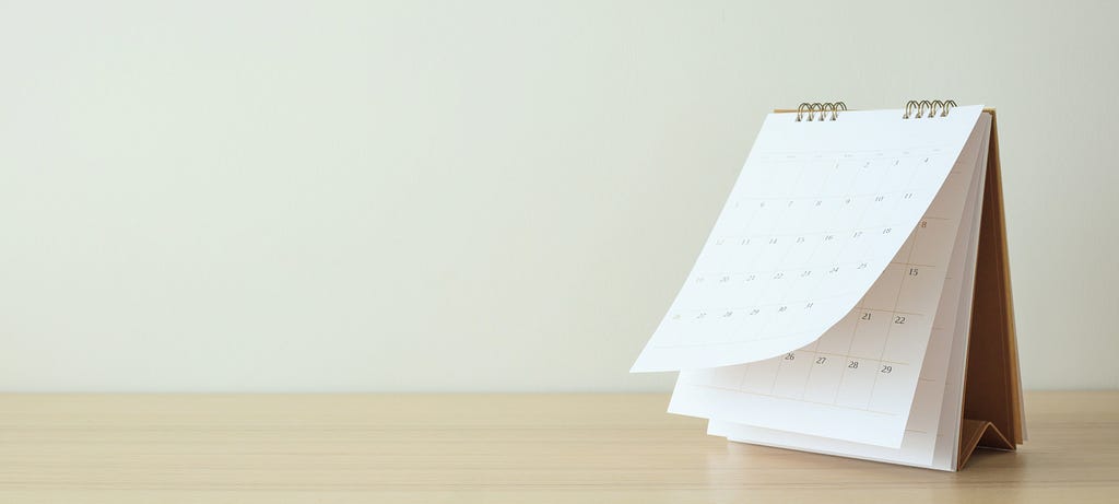 Standing calendar with pages flipping on a light wooden table