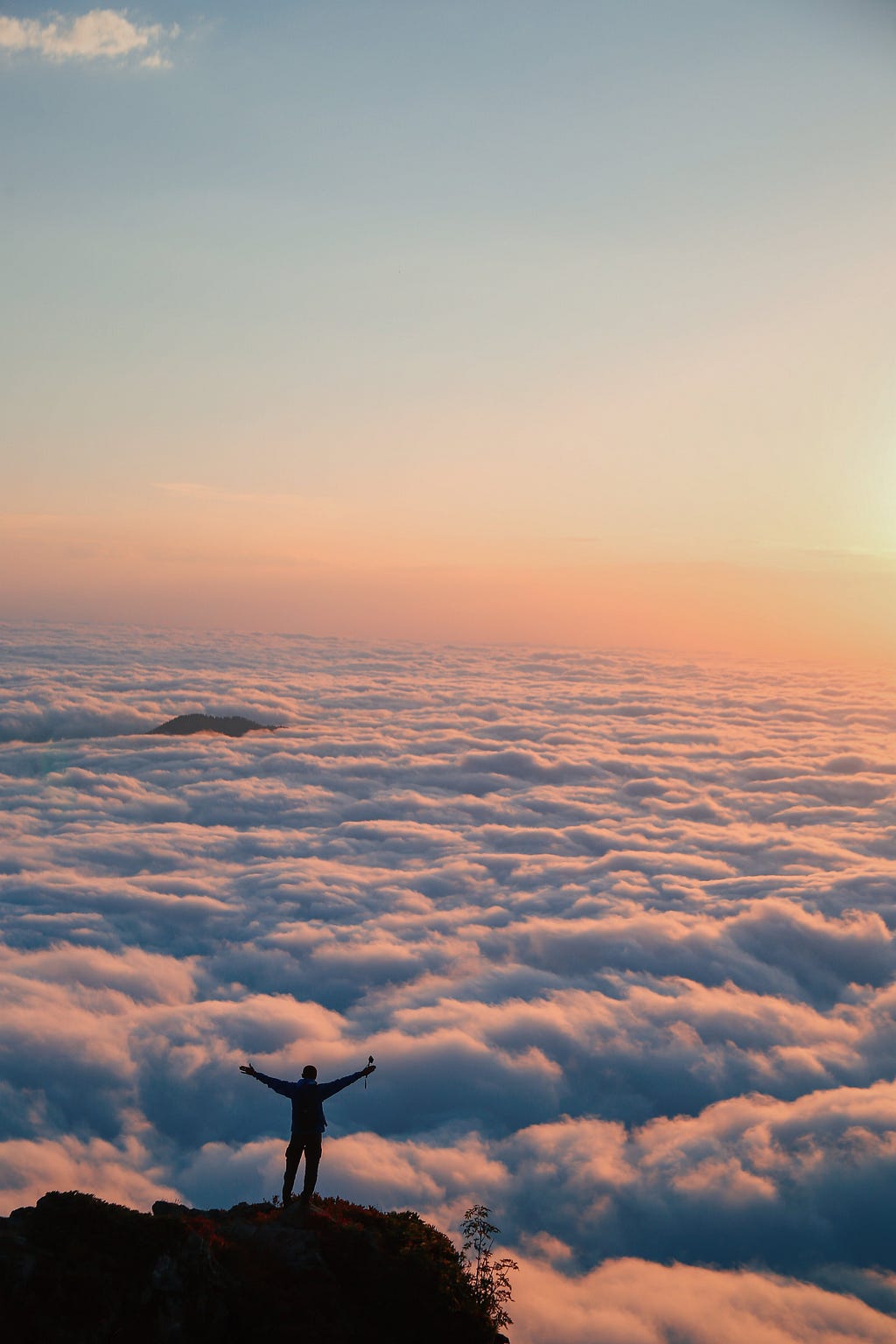 A person standing at the edge of a cliff or on a high peak