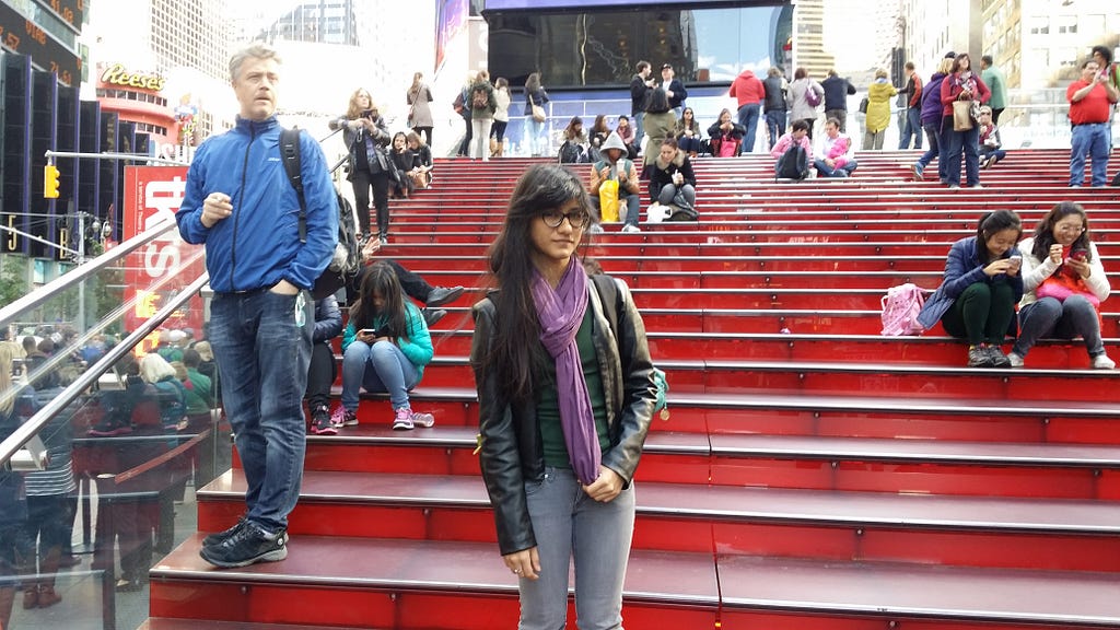 The author standing on the iconic red stairs at Times Square