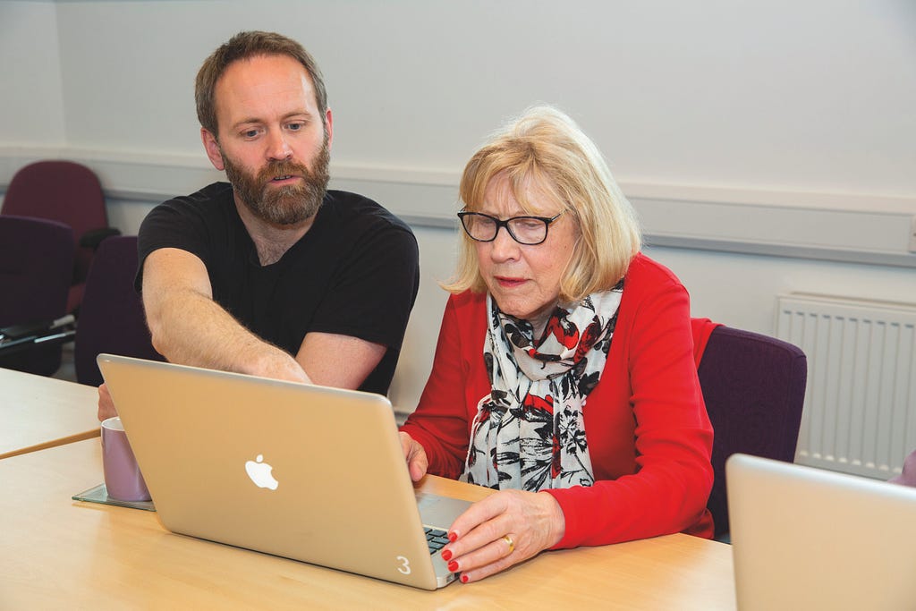 Man and woman sitting at desk looking at laptop