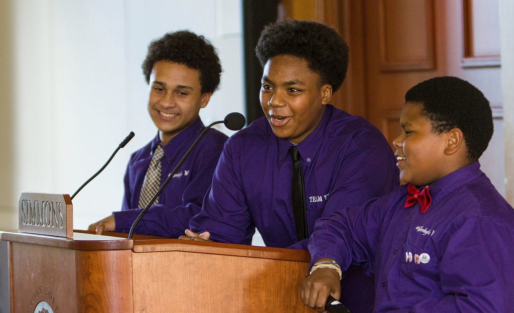 Three students speak at a podium