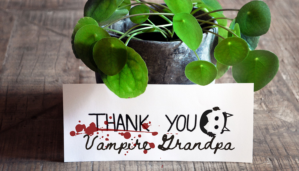 A potted plant and n envelope with text: Thank you Vampire Grandpa. There is a blood splatter and a doodle of an old vampire