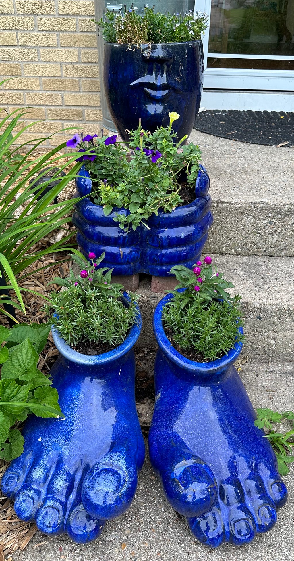 Garden creature — cobalt blue feet, hands, and half-head planted with flowers