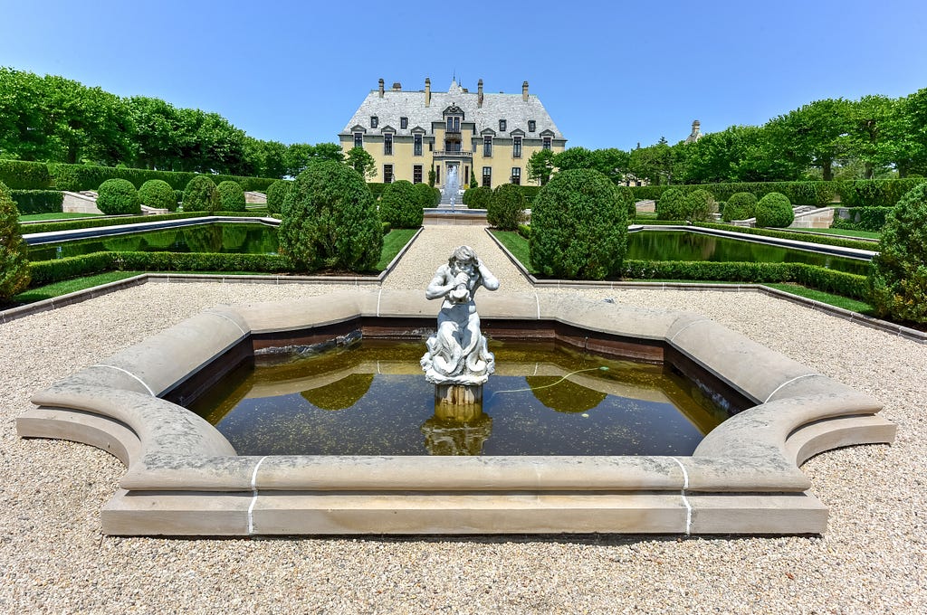 Front view of Oheka Castle with elaborate statue in the middle of a fountain