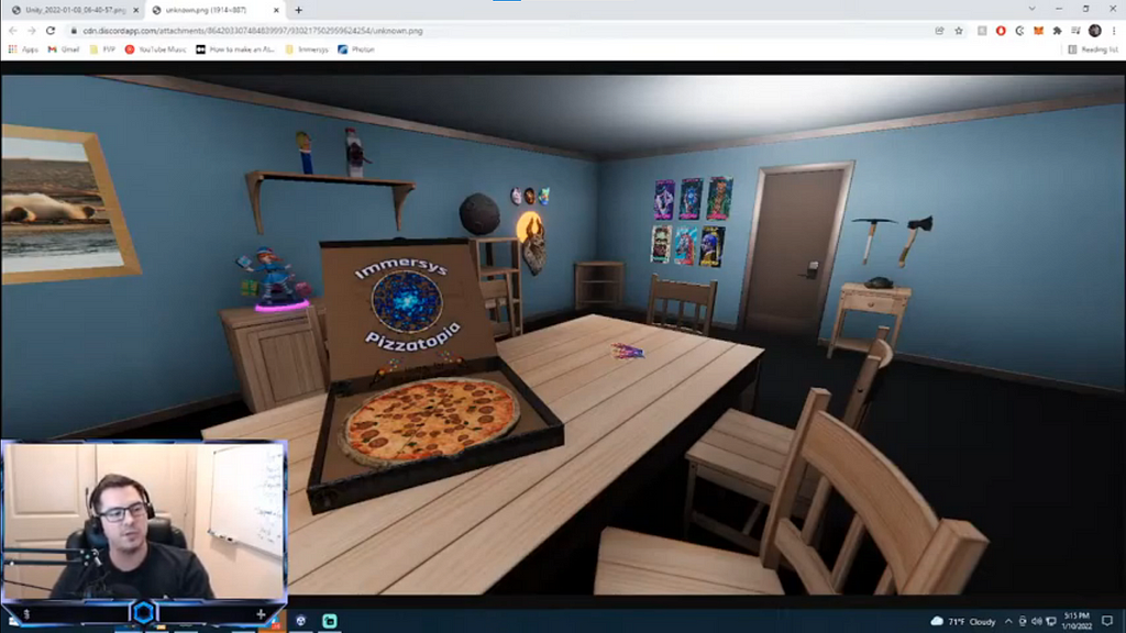 A plain blue room with a low ceiling shown behind webcam footage of an Immersys CEO. An open pizza box sits on a digital pine table. The room has furniture of a matching set with a few figurines and game objects as decoration.