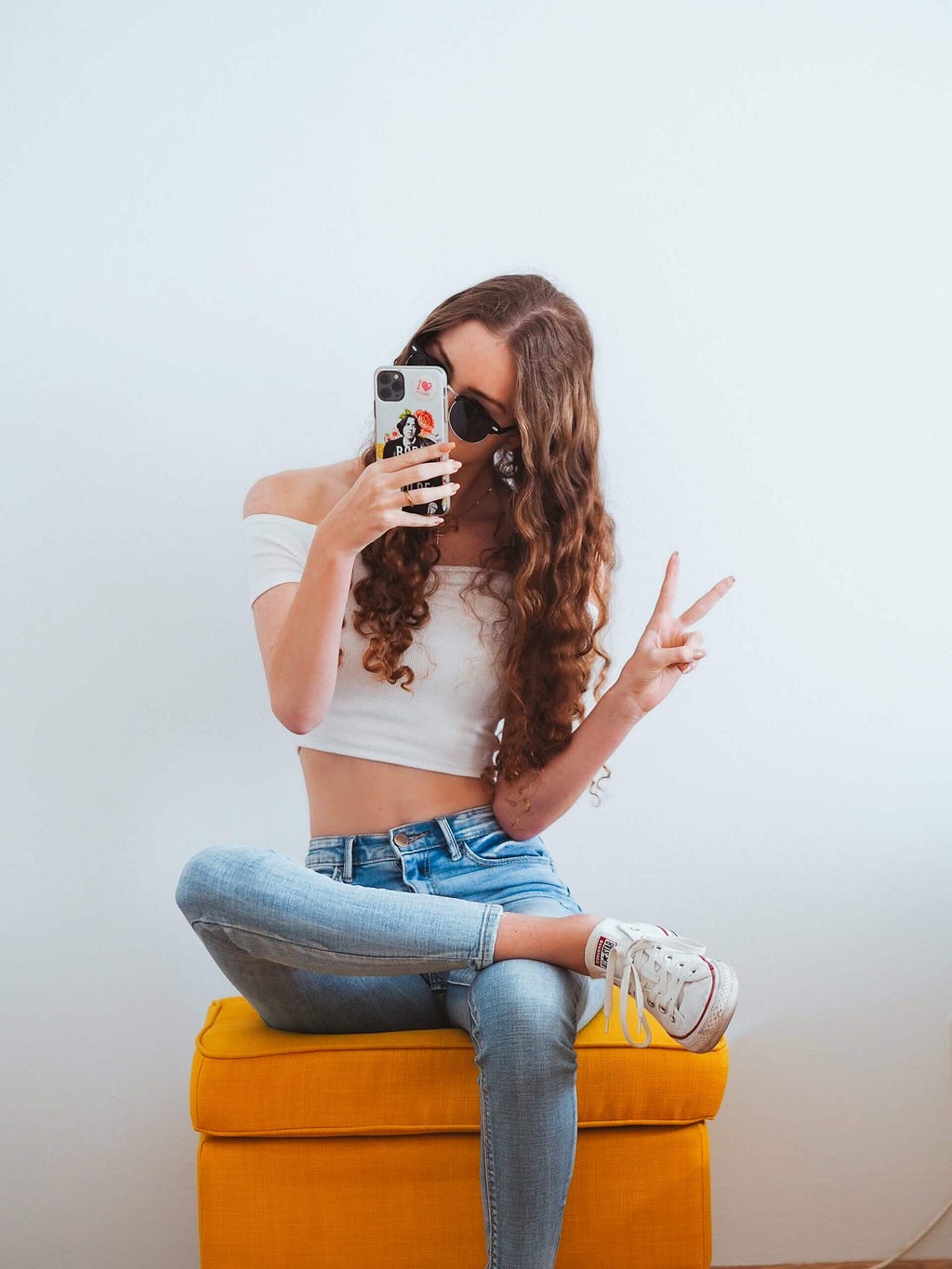 A girl influencer siting on a couch taking a selfie.