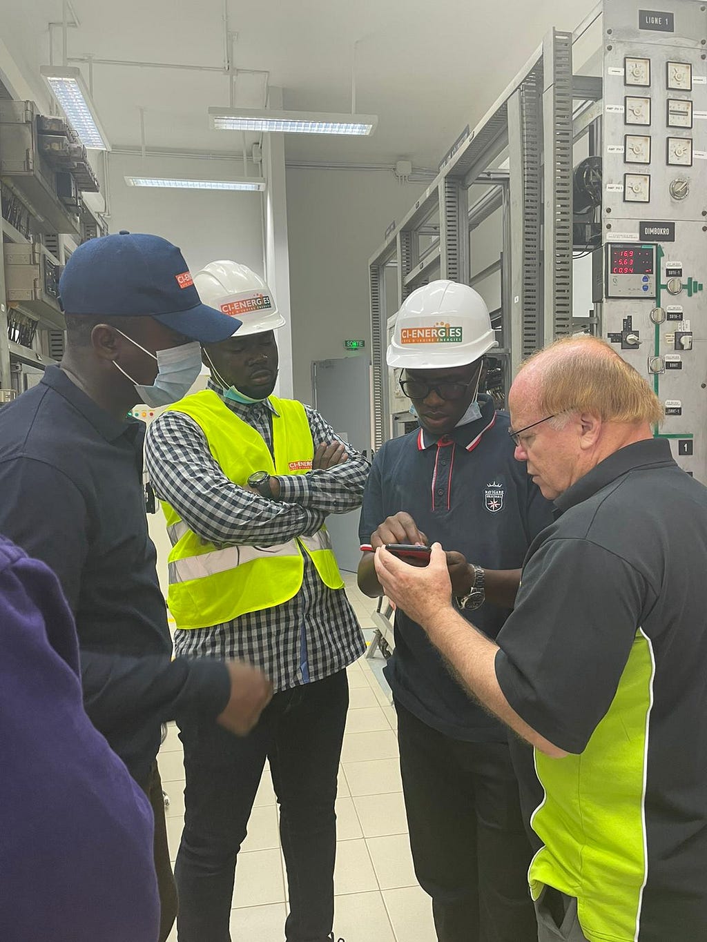 Power Africa and CI-Energies teams inspect devices in an electric station room