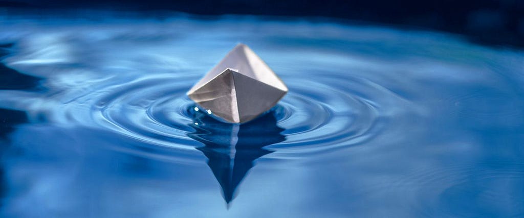 Paper boat on blue water