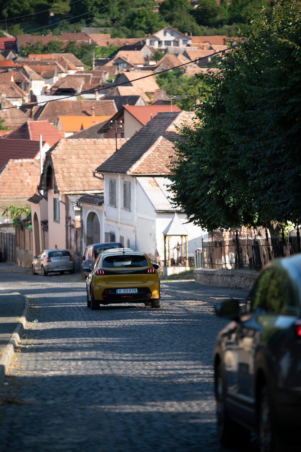 Peugeot e208 driving on the narrow streets of Sibiu county pictured from the back