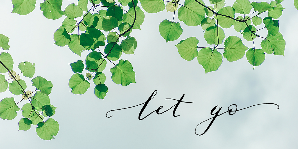‘Let go’ in calligraphy overlayed on an image of the sky and  leaves