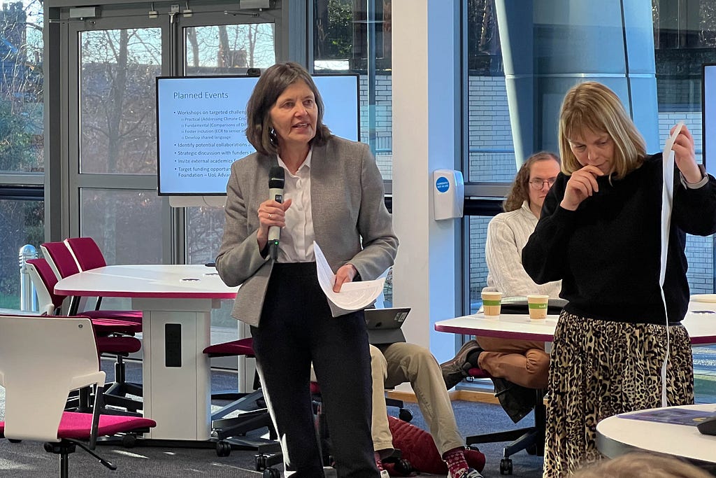 Professor Anne Forster and Dr Sarah Astill present their ideas to the collaborative lab — Dr Astill is holding up a piece of poster paper, Prof Forster is holding a microphone.