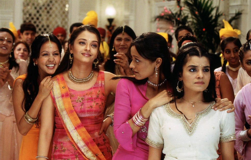 Four young women dressed in south asian style standing in the foreground of a party scene.