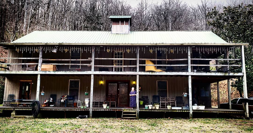 Matushka Anastasia Williams stands on the front porch of her two-story hand-built home in Agape Hollow
