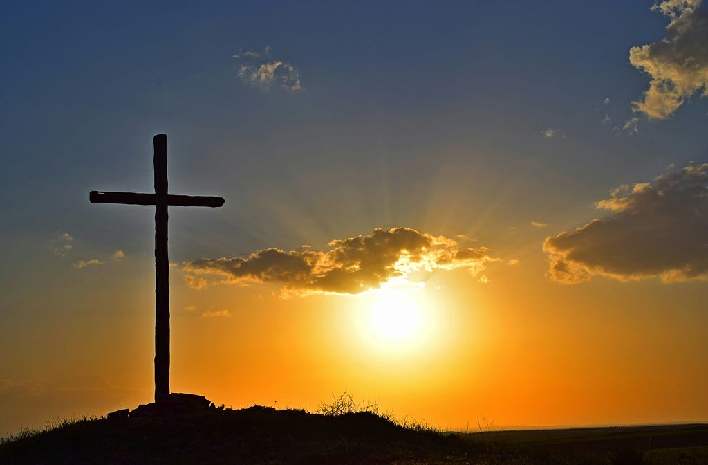 The sun setting behind a cross