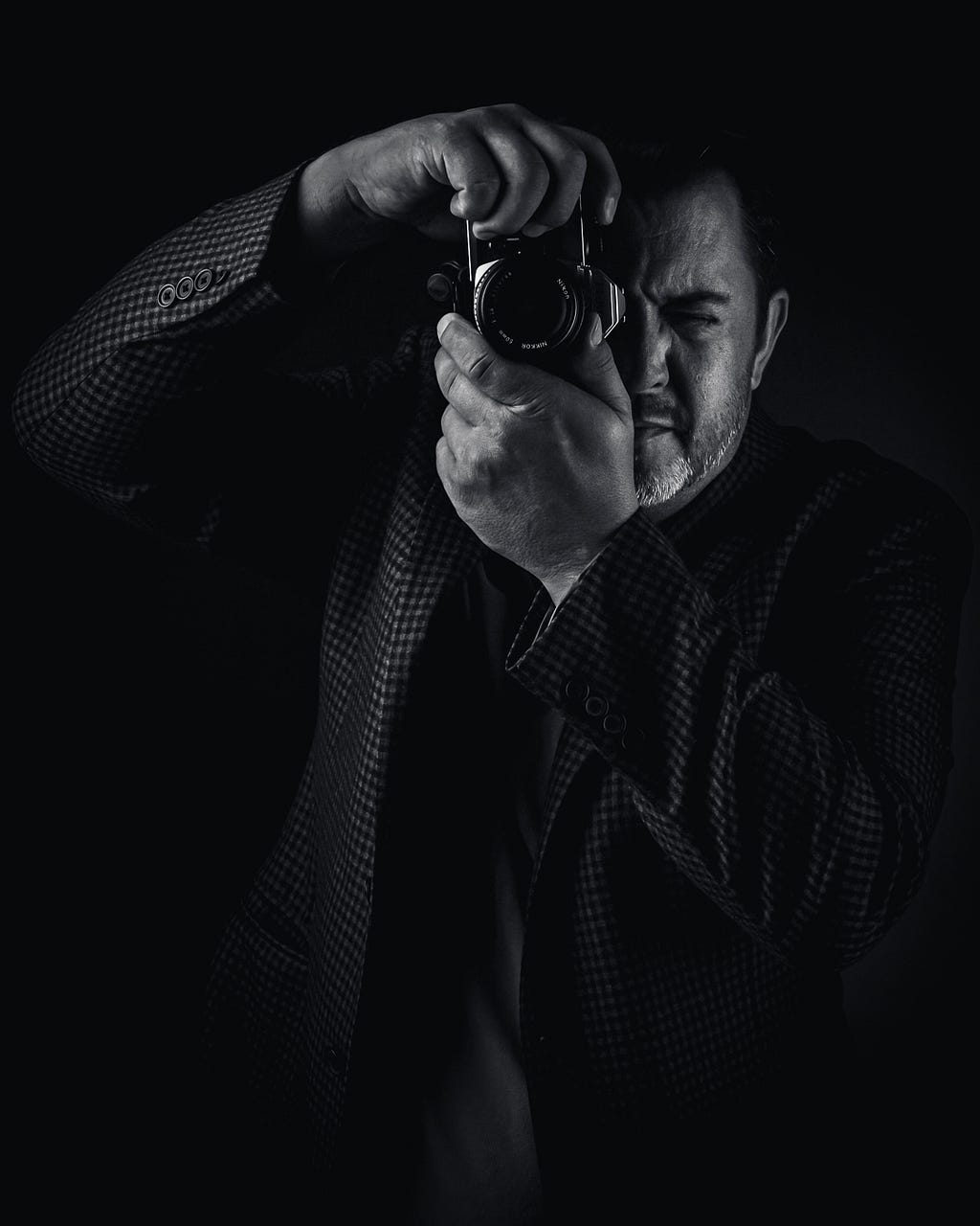 Robert Schall holding a 35mm film camera from Nikon shot in high contrast black and white