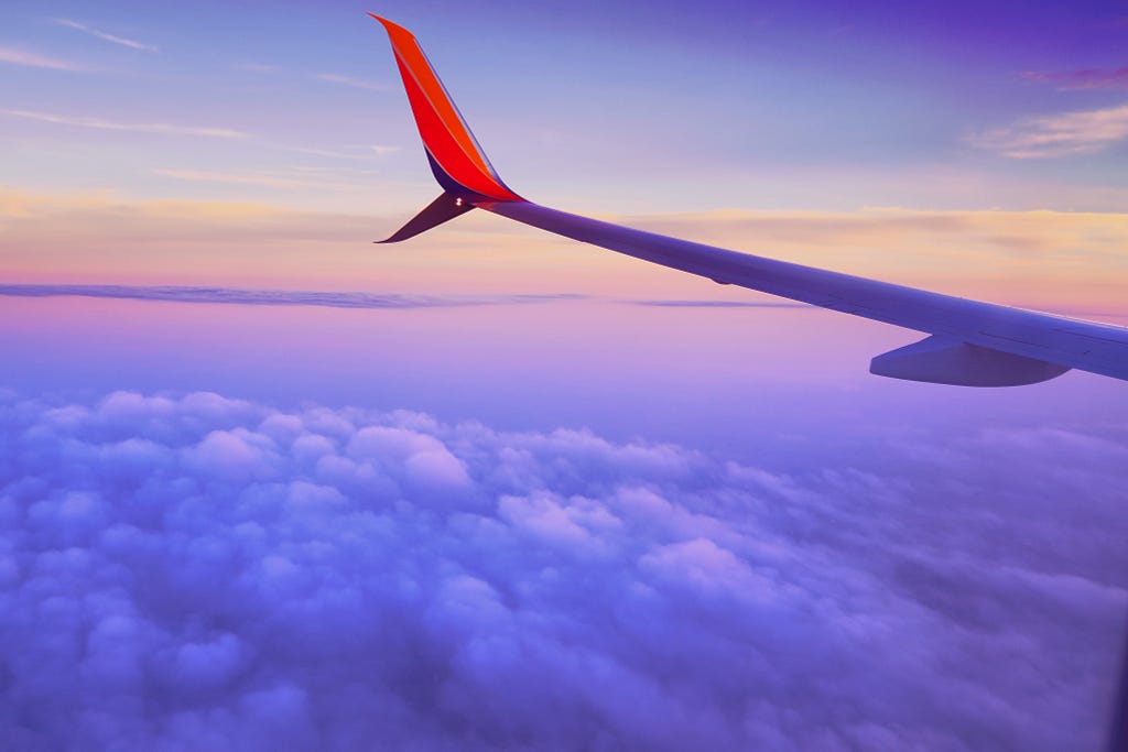 High altitude flight (view of wing from a seat, with clouds below)