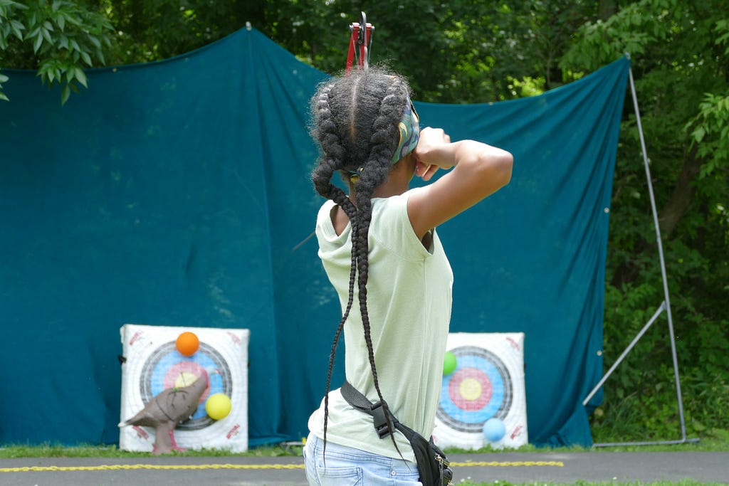 Girl takes aim with a bow and arrow