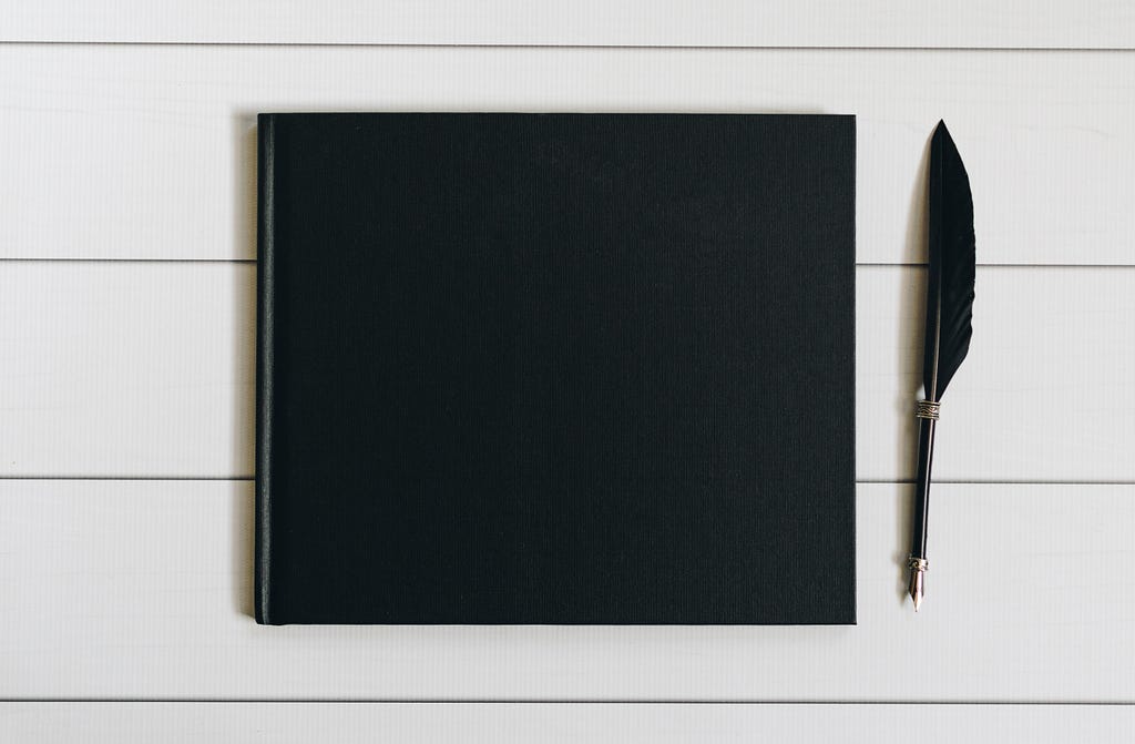 a blank black notebook and quill to represent the freedom to style your own brand story