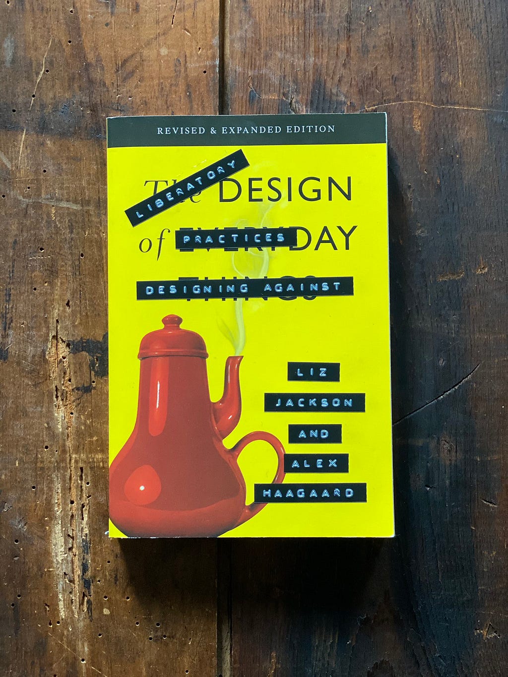 A softcover copy of the book The Design of Everyday Things, which has been altered with retro stick-on embossed letter strips, so the title now says, “Literatory Design Practices: Designing Against” and the authors now appear to be “Liz Jackson and Alex Haagaard”