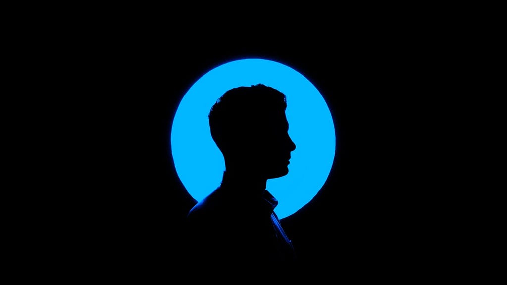 Sombra de um homem de perfil iluminado por uma luz azul atrás.
