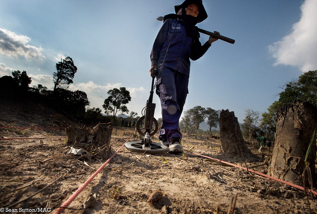 Image of a team member from Mines Advisory Group checking for mines with a scanning device.