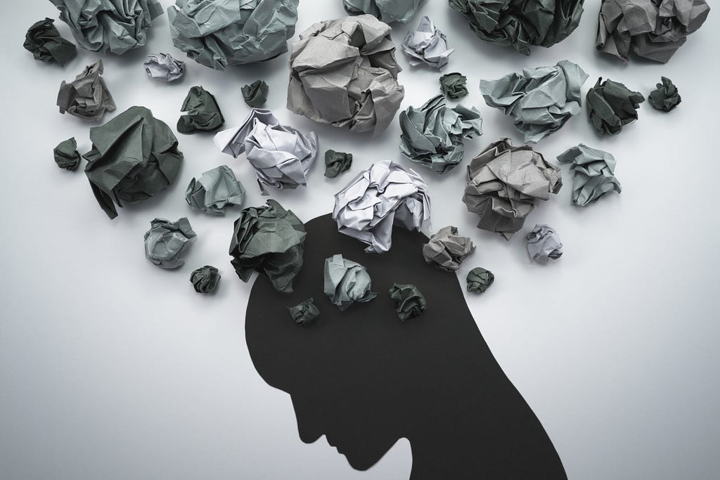 Black silhouette of a human head with crumpled papers floating above.