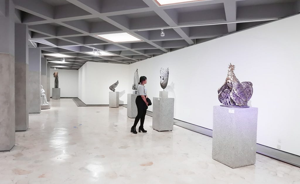 A woman views sculptures in an art gallery.