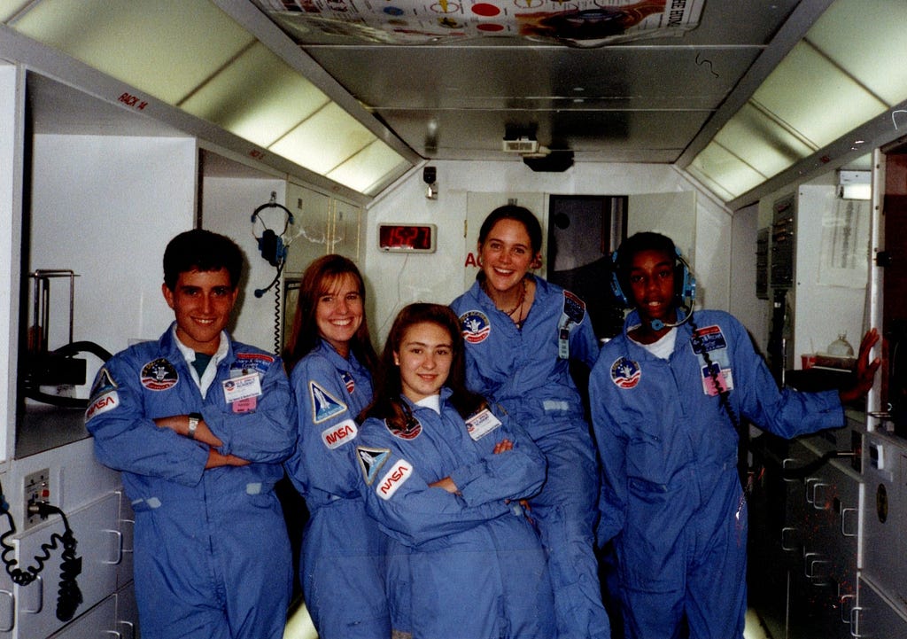 Five teenagers wearing NASA flight suits on a mockup of the space shuttle.